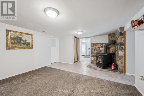 Stone fireplace with wood stove and framed painting - 2063 George Street Howick