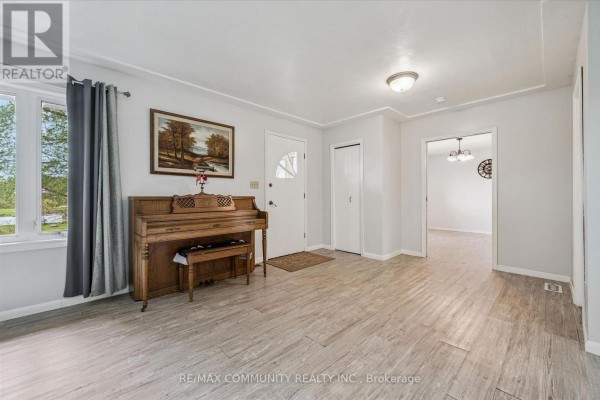 Living room with light grey walls, light wood flooring, a large window, and a wooden upright piano. - 2063 George Street, Howick