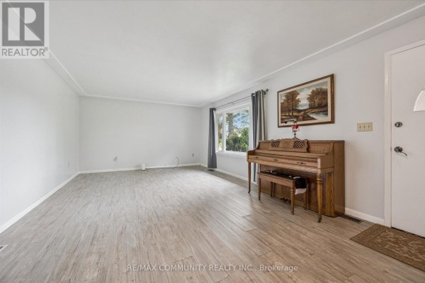 Living room with light grey walls, light wood flooring, a large window, and a wooden upright piano. - 2063 George Street, Howick