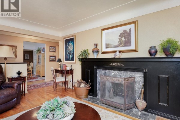 Living room with fireplace, leather chair, desk, and view into dining room. - 2064 Lansdowne Rd, Oak Bay