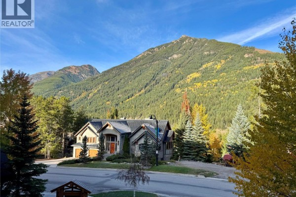 A large house with a stone facade and mountain backdrop. - 2064 Summit Drive Unit# 106, Panorama