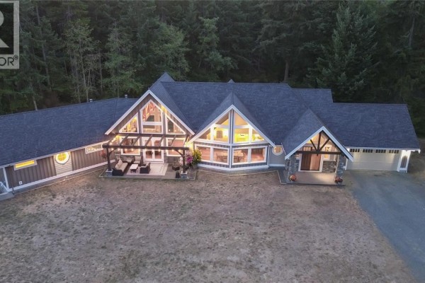 Modern house with large windows, wooden beams, stone accents, and a garage. - 2065 Sanders Rd, Nanoose Bay