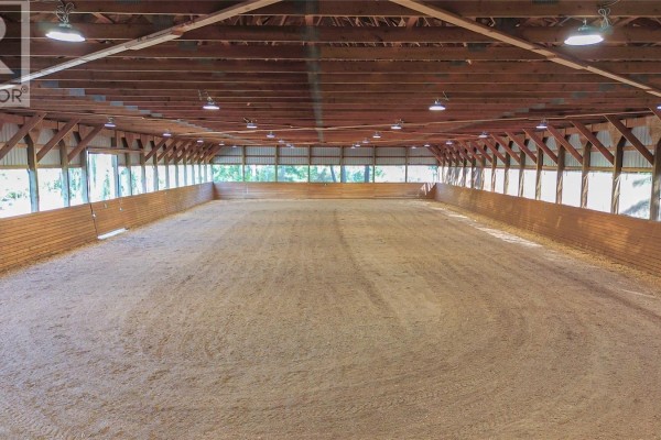 Interior view of an indoor riding arena with a dirt floor and wooden walls. - 2065 Sanders Rd, Nanoose Bay
