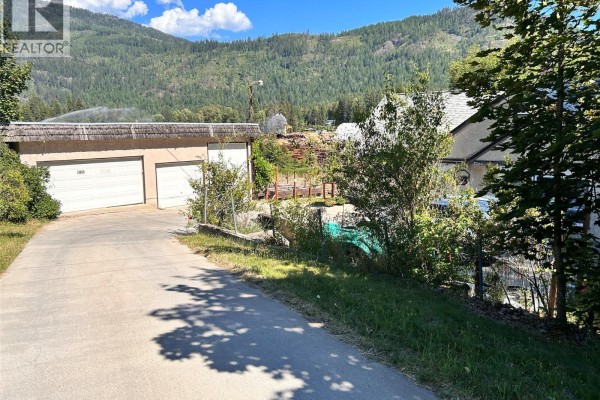 Concrete driveway leading to a detached three-car garage with mountains in the background. - 2066 Caughlin Road, Fruitvale