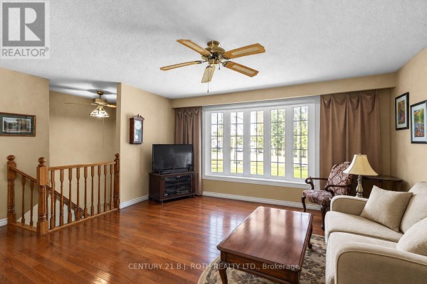 Living room with wood floors, a bay window, and tan walls with brown curtains. - 2067 Marchmont Road, Severn