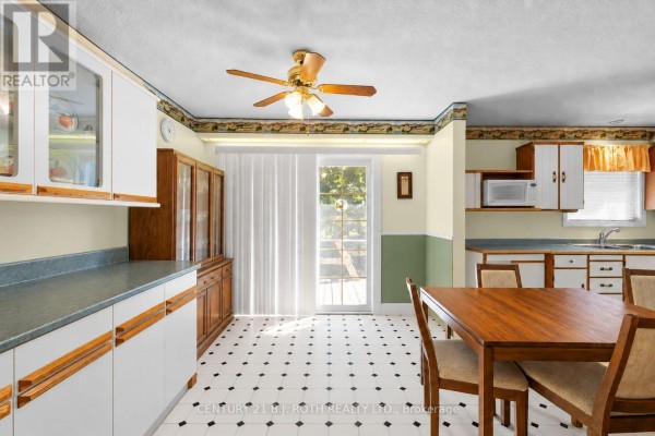 Kitchen and dining area with white cabinets, wooden chairs, and a sliding glass door. - 2067 Marchmont Road, Severn