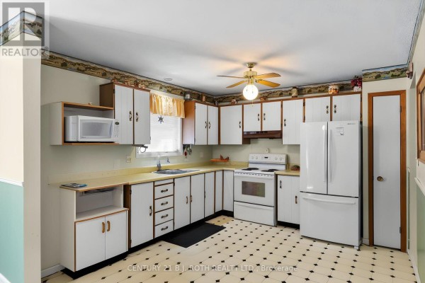 Kitchen with white cabinets, white appliances, and a black and white tiled floor. - 2067 Marchmont Road, Severn