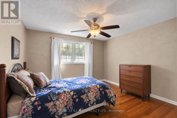 Bedroom with a king-size bed, wooden dresser, and cream-colored walls. - 2067 Marchmont Road, Severn
