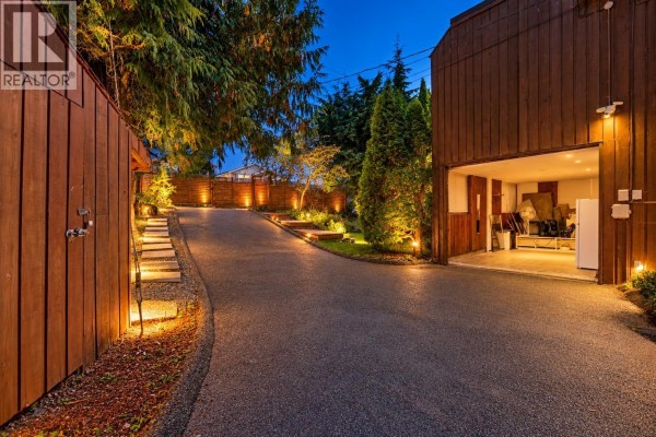 Asphalt driveway leading to an open garage with exterior lighting. - 2069 Westview Drive, North Vancouver