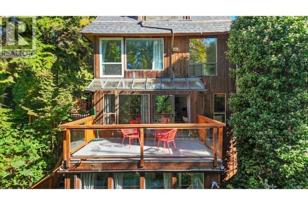Wooden deck with glass railings and red chairs overlooks a forested area. - 2069 Westview Drive, North Vancouver