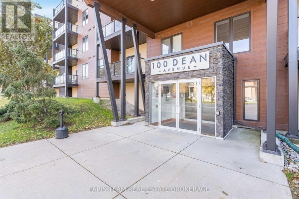 Front entrance of the building with prominent signage and snow around. - 207 - 100 Dean Avenue, Barrie