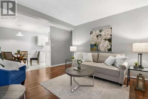 Living room and dining area with hardwood floors, light grey walls, and modern furniture. - 207 - 190 Elgin Street W, Arnprior