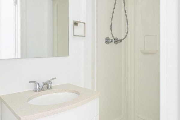 Bathroom with vanity sink, countertop, chrome faucet, mirror, and standing shower with chrome fixtures. - 207 - 198-200 Queen Street W, Toronto