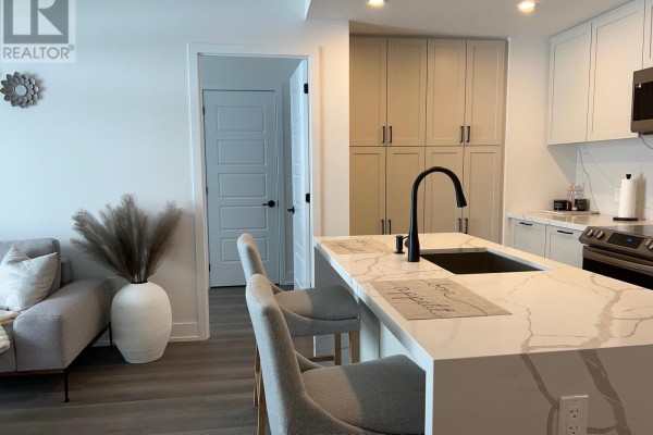 View from the kitchen island showing a hallway, entryway, and kitchen cabinetry. - 207 - 415 Sea Ray Avenue, Innisfil