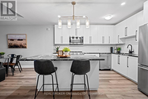 Open concept kitchen and living area with a gray island and dining table visible. - 207 - 51 David Street, Kitchener