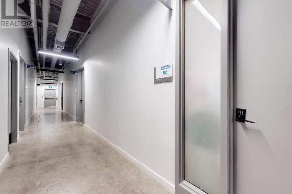 Interior hallway with concrete floors, white walls, and multiple doors leading to units. - 207 - 52 Scarsdale Road, Toronto