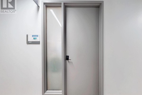 Close-up of unit 207 door with a digital lock and frosted glass side panel. - 207 - 52 Scarsdale Road, Toronto