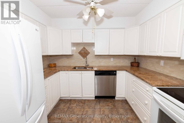 Kitchen with white cabinets, granite countertops, a stainless steel sink and dishwasher, and tiled flooring. - 207 - 800 Gordon Street, Thunder Bay