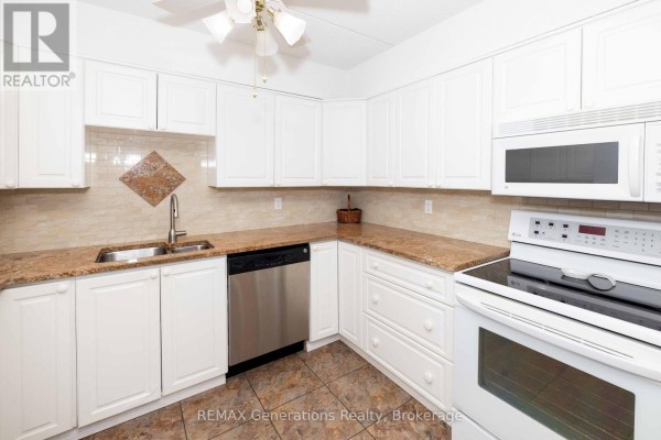 Kitchen with white cabinets, granite countertops, stainless steel dishwasher, and a white stove and microwave. - 207 - 800 Gordon Street, Thunder Bay