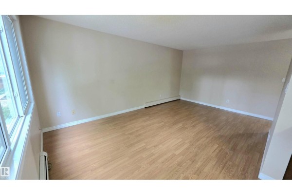 View from hallway into kitchen and living room with mirrored closet doors. - #207 10415 93 St Nw Nw, Edmonton