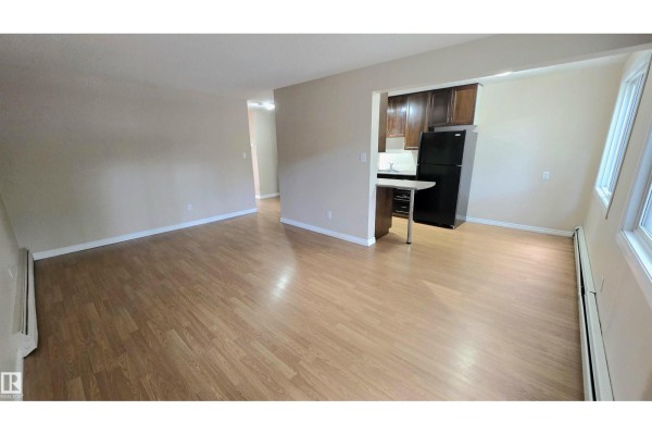 Kitchenette with dark wood cabinets, black appliances, and a breakfast bar. - #207 10415 93 St Nw Nw, Edmonton