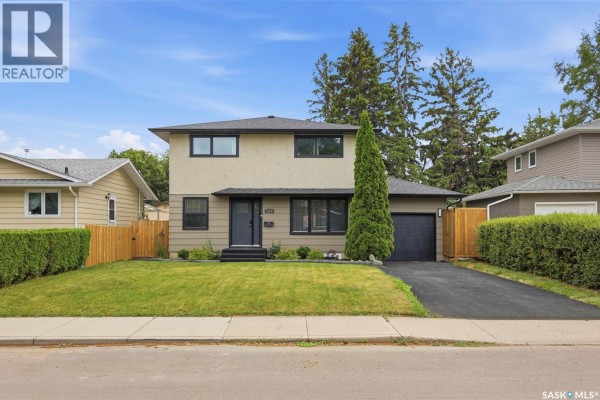 Front exterior view of a two-story house with a garage and manicured lawn. - 207 113th Street W, Saskatoon