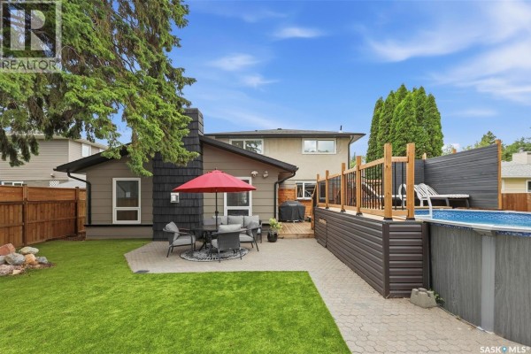 Backyard view of a house featuring a pool, patio, and outdoor seating area. - 207 113th Street W, Saskatoon