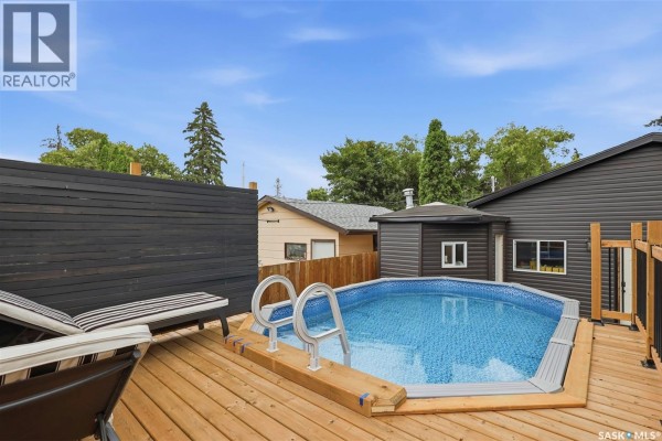 Above-ground swimming pool on a wooden deck with lounge chairs and privacy fencing. - 207 113th Street W, Saskatoon