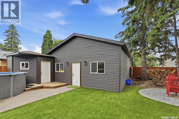 Exterior view of a detached garage and shed in a grassy backyard with a patio. - 207 113th Street W, Saskatoon