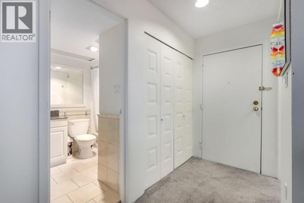 Apartment entrance hallway with white double closets and a doorway to the bathroom. - 207 1450 Laburnum Street, Vancouver
