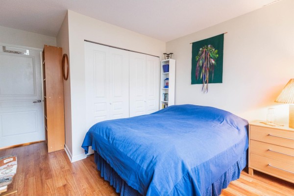 Bedroom showing the bed, closet doors, a bookshelf, and a window. - 207 15466 North Bluff Road, White Rock