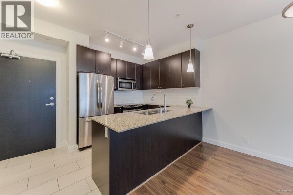 Kitchen featuring stainless steel appliances, granite island, and modern fixtures - 207 240 Francis Way, New Westminster