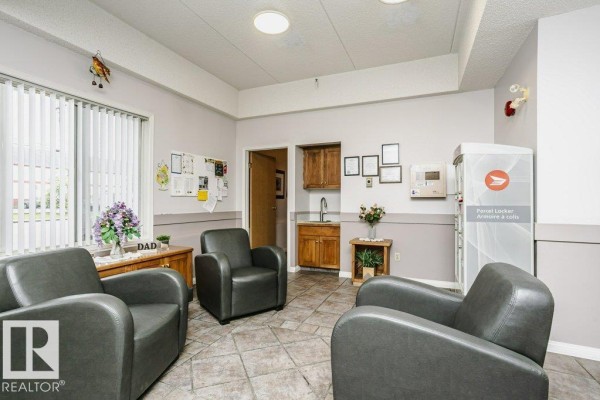 Exterior view of a building with large windows overlooking a pond with fountains and surrounding trees. - #207 4906 47 Av, Leduc