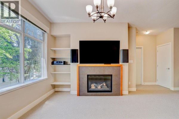 Modern building entrance with double glass doors and expansive glass windows. - 207 5955 Iona Drive, Vancouver