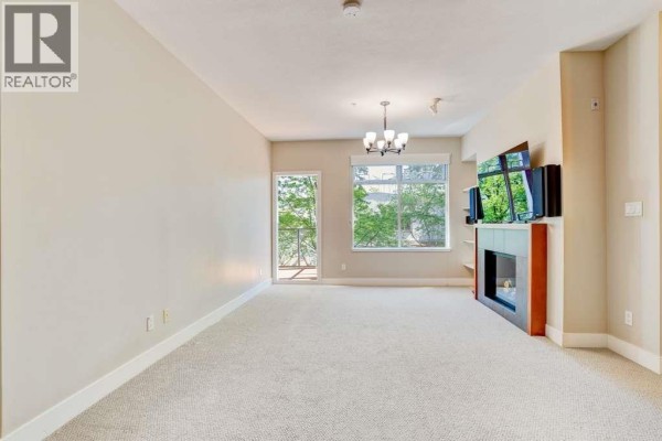 View of the open-concept living area featuring a kitchen island and living space. - 207 5955 Iona Drive, Vancouver