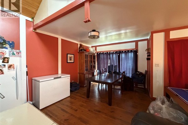 Dining area with a large wooden table, chairs, a china cabinet, and a white chest freezer. - 207 Main Street, Hudson Bay