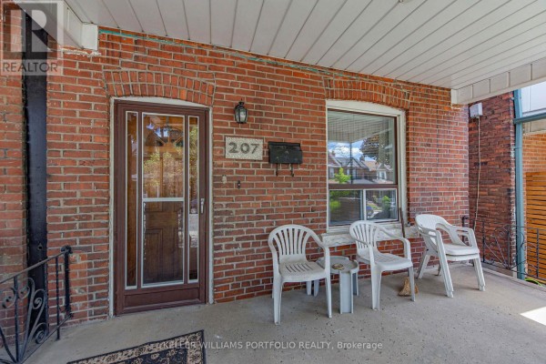 Close-up of the brick front porch with a glass-paneled door and white plastic chairs. - 207 Symington Avenue, Toronto