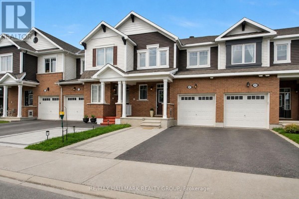 View of townhouse exteriors with brick and dark brown vinyl siding, garage doors, and front porches. - 207 Willow Aster Circle, Ottawa
