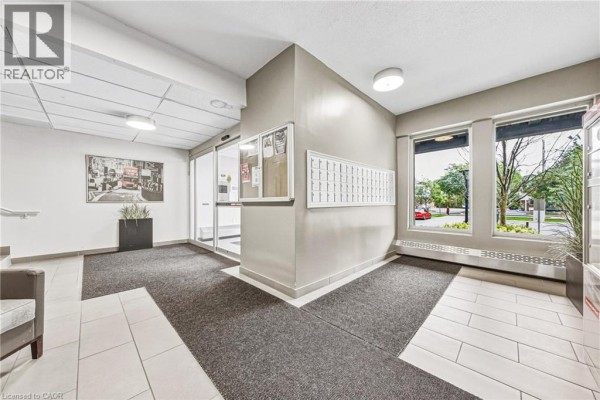 Apartment building lobby with mailboxes, seating, and a large window. - 2077 Prospect Street Unit# 104, Burlington