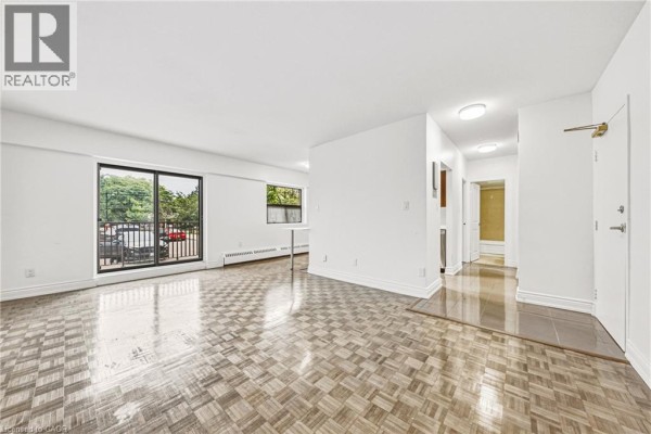 Living room with parquet flooring, white walls, and large sliding glass doors. - 2077 Prospect Street Unit# 104, Burlington