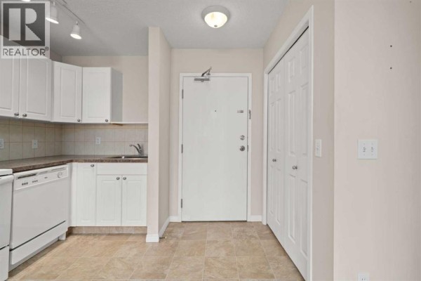 Apartment entryway with white bi-fold doors, white bi-fold closet, and beige tile floor. - 208, 1010 Railway Street, Crossfield