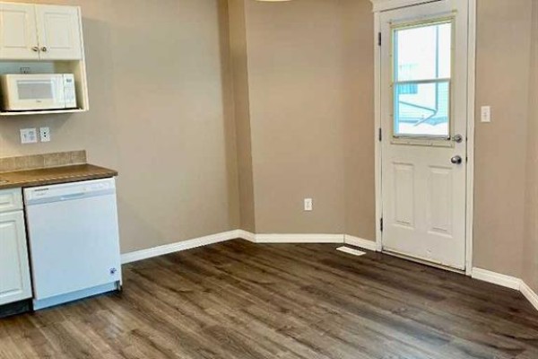 Kitchen area with dishwasher, microwave, and door to exterior. - 208, 10150 121 Avenue, Grande Prairie