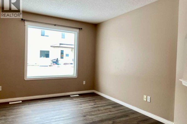 Living room with large window showing view of exterior buildings. - 208, 10150 121 Avenue, Grande Prairie