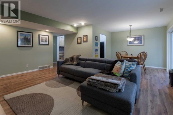 Living room and dining area with wooden table, chairs, and sectional sofa. - 208, 2207 8 Avenue S, Lethbridge