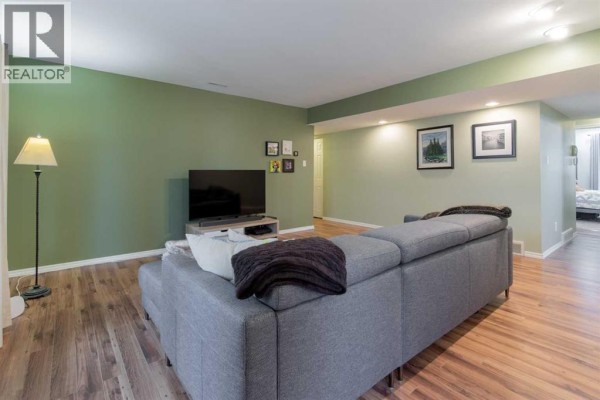 Living room with grey sectional sofa, television on a stand, and light green walls. - 208, 2207 8 Avenue S, Lethbridge