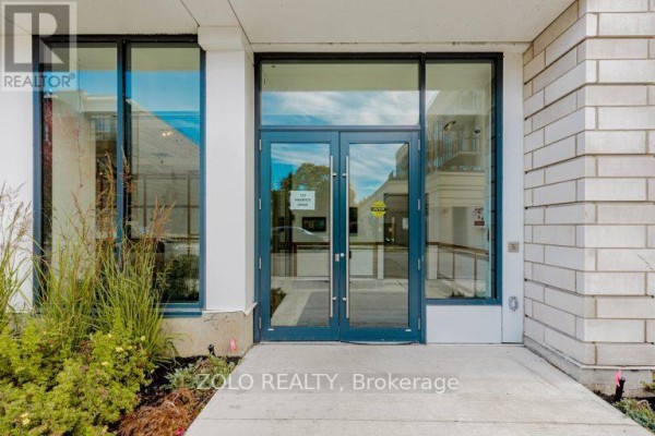 Double glass doors leading into the building lobby with surrounding large windows. - 208 - 123 Maurice Drive, Oakville