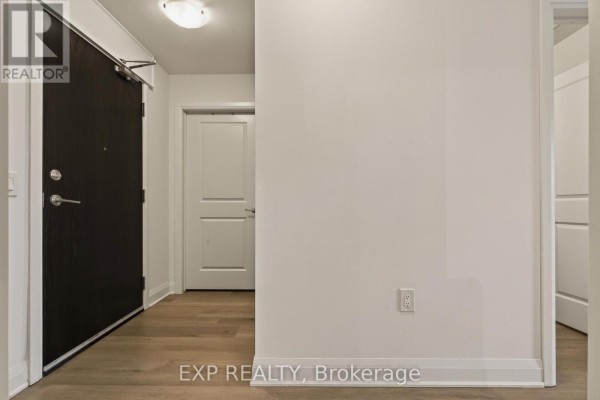 Apartment entrance hallway with a dark door, white doors, and wood floors. - 208 - 1936 Rymal Road E, Hamilton