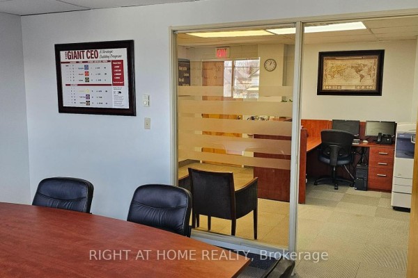 View into office space with desks and computers through a frosted glass partition. - 208 - 200 Bond Street W, Oshawa
