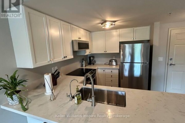 Kitchen with white cabinets, stainless steel refrigerator, and quartz countertops. - 208 - 625 St David Street S, Centre Wellington