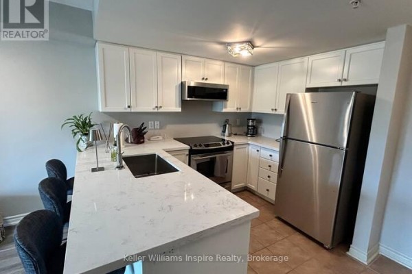 Kitchen with white cabinets, quartz island with seating, stainless steel appliances. - 208 - 625 St David Street S, Centre Wellington